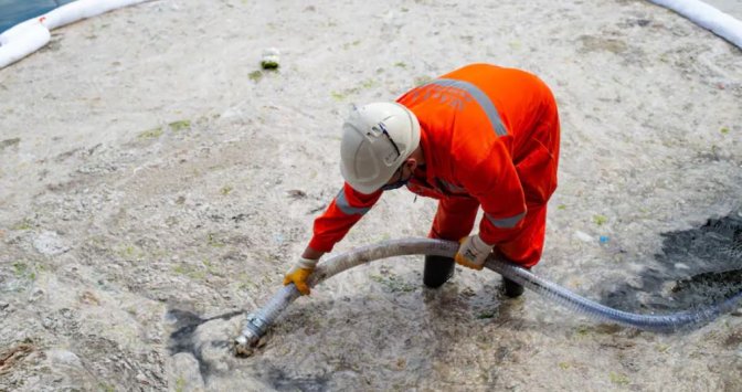 Un employé de la ville d'Istanbul entrain d'aspirer une épaisse couche de « morve de mer »