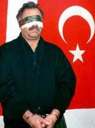L'arrestation de Abdullah Öcalan posant devant le drapeau turc